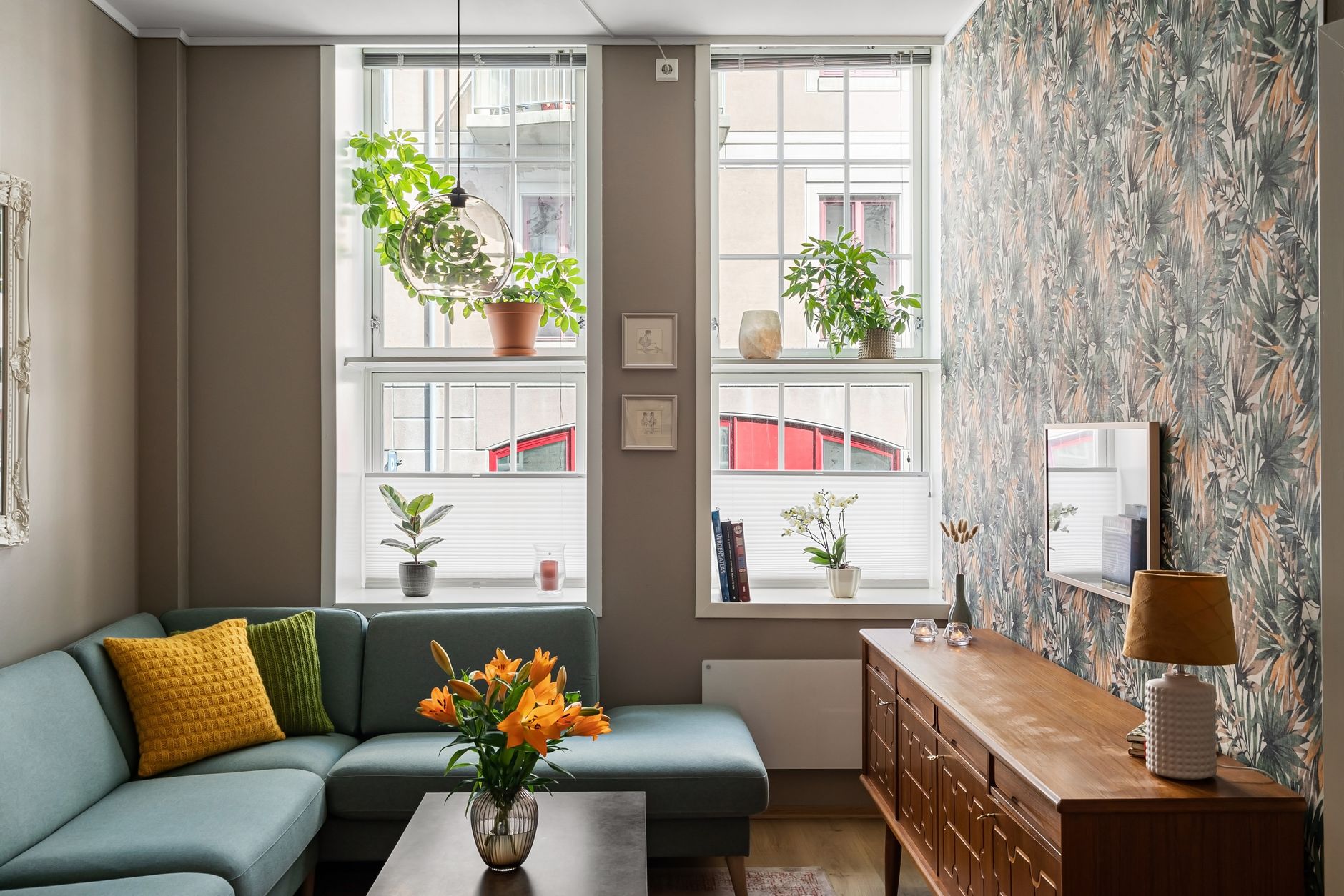 A bright living room with large windows, plants and natural light.