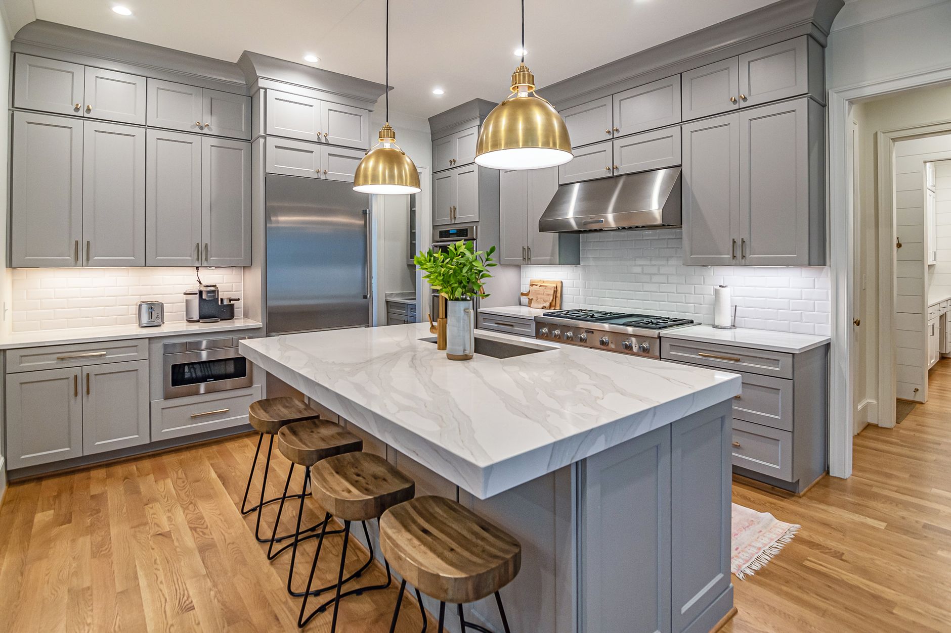 A finished kitchen with a marble island and warm pendant lights.
