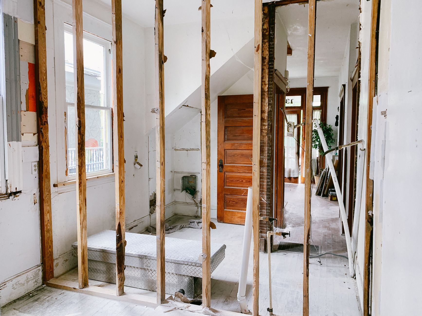 The same room before renovation: bare plaster walls, exposed wooden beams and a door frame.
